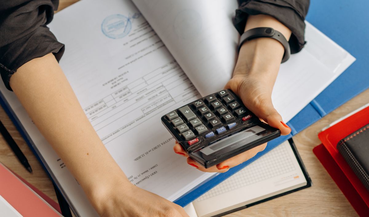 Manager using a calculator over budget documents to plan corporate language training cost per employee