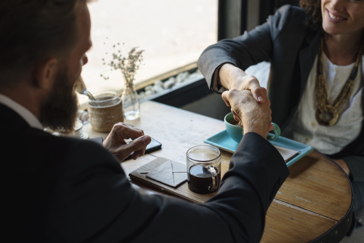 Two professionals shaking hands over a finalized language training vendor agreement