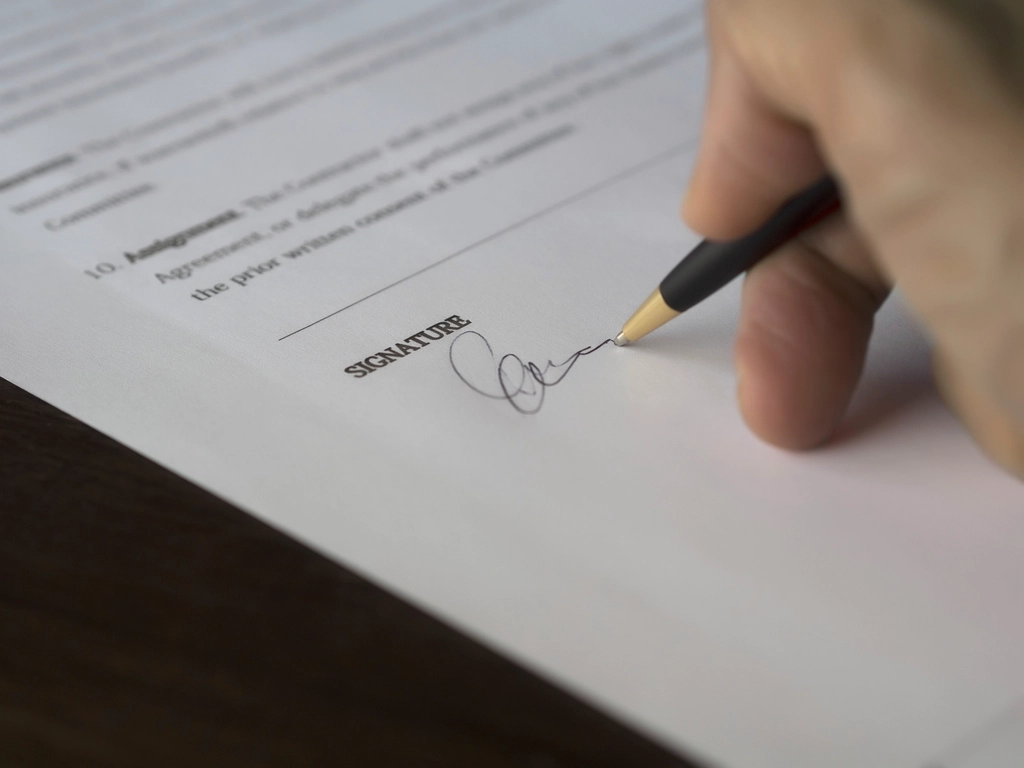 Lawyer reviewing and signing a bilingual contract document at an office desk